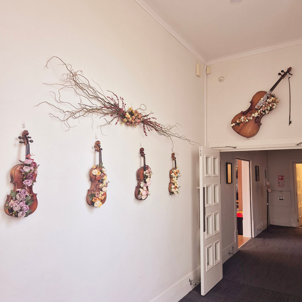Decorated violins and floral artwork displayed on the café wall