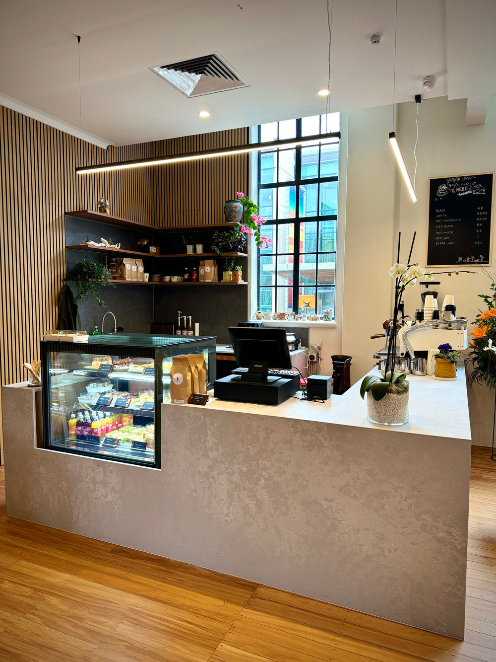 Café counter and pastry display beside a tall window