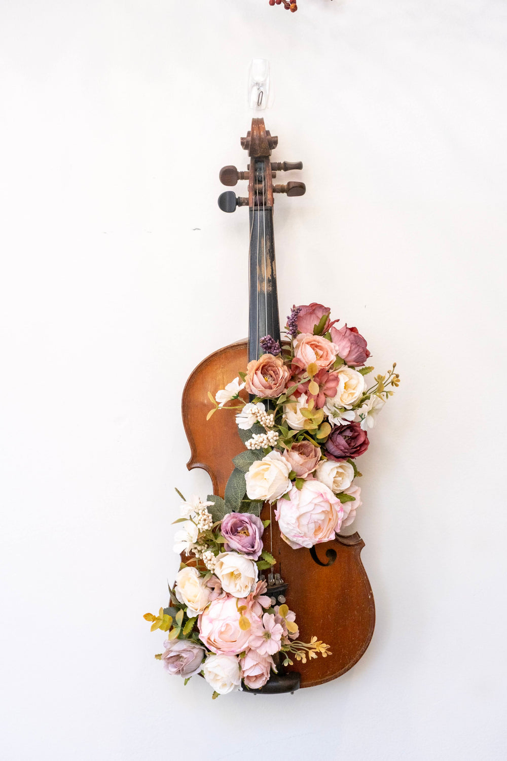 A floral violin decoration displayed on a white wall